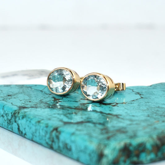 Gold earrings with clear gemstones on a turquoise stone